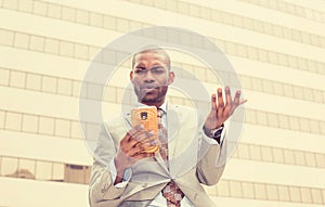 Closeup unhappy young man in suit talking texting on cellphone outdoors