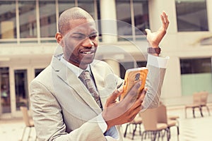 Closeup unhappy young man in suit talking texting on cellphone outdoors photo