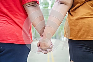 Closeup of unidentified fat couple holding hands