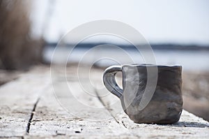 Closeup of unique handmade cup with folk sign with blurred lake on background