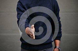 Closeup of an unknown businessman holding his hand out for a handshake in a outside in the city