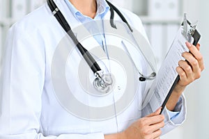 Closeup of unknown doctor woman standing with medication history records form at hospital. Health care, insurance an