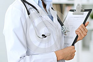 Closeup of unknown doctor woman standing with medication history records form at hospital. Health care, insurance an