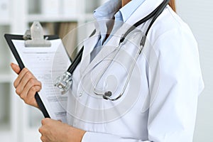 Closeup of unknown doctor woman standing with medication history records form at hospital. Health care, insurance an