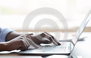 Closeup of unrecognizable black female working on laptop, typing on computer keyboard photo