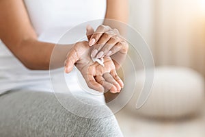 Closeup of unrecognizable black woman with moisturising cream on her hands