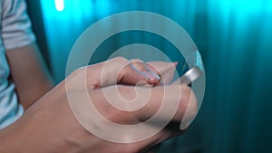 Closeup of unrecognizable man texting message on smartphone sitting on sofa in room with soft lighting. Close-up of male