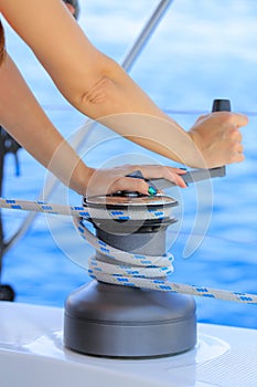 Yachtsman hand dealing with yacht ropes on halyard winch photo