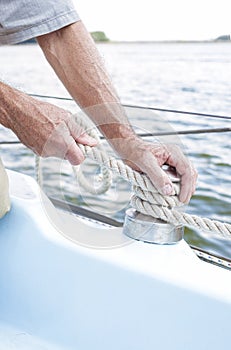 Closeup up of Yachtsman Hands Dealing with Yacht Ropes.