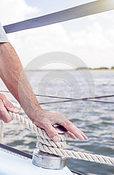 Closeup up of Yachtsman Hands Dealing with Yacht Ropes