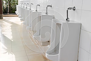 Closeup urinals white color in men`s public restroom with light