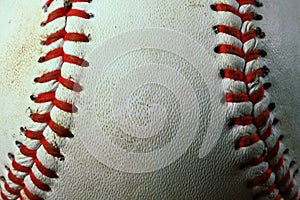 Closeup of a used white baseball with red seams.