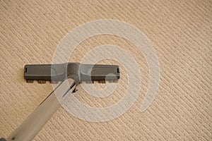Closeup of the vacuum cleaner gray tube and brush on the carpet