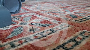 Closeup of a vacuum cleaner. Person vacuum-cleaning a carpet