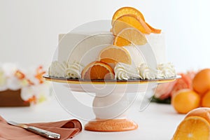 Closeup of vanilla cake with orange slices on cake stand