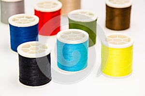 Closeup of various colorful sewing threads on the white surface