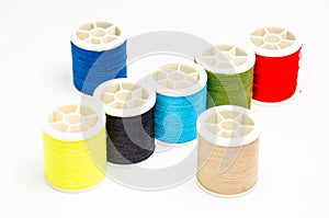 Closeup of various colorful sewing threads on the white surface