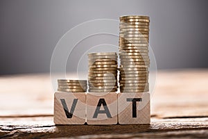 Vat Text Written On Wooden Blocks With Stacked Coins photo