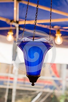 Closeup vertical shot of a blue glass lamp hanging on three iron chains