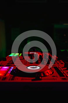 Closeup vertical shot of an illuminated DJ turntable with various track controls