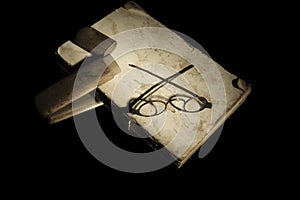 Closeup very old spectacles eyes glasses with wooden box on very old open book lying on mirror for reflection