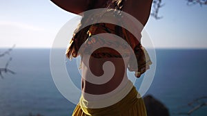 Closeup video portrait of sensual young brunette woman in yellow dress, happily dancing outdoors isolated on blurry sea