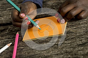 Closeup view of an African-American girl colouring a heart shape