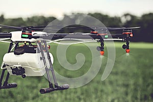 Closeup view of agriculture drone spraying water fertilizer on the green field