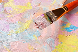 Closeup view of artist`s palette with mixed pastel paints and brush as background