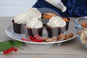 Closeup view of baker decorating tasty cupcake with creamy