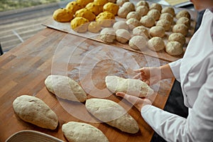 Closeup view on baker hands preparing formed bread dough for proofing