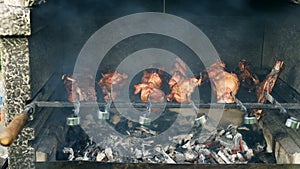 Closeup view of barbeque brazier cooking big turkey or chicken meat leg on metal skewers set flaming on burning coal