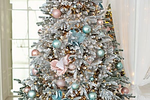 CloseUp view of beautiful decorated Christmas tree in pink and blue colors in living room.