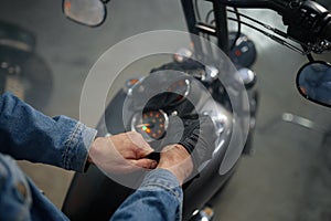 Closeup view on biker hand wearing leather gloves over motorcycle gas tank