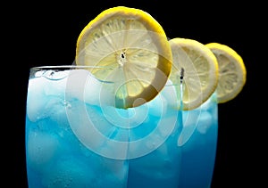 Closeup view of blue lagoon cocktails with ice cubes on black