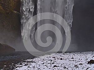 Closeup view of the bottom of famous waterfall SkÃ³gafoss with spray in winter with snow in the south of Iceland.