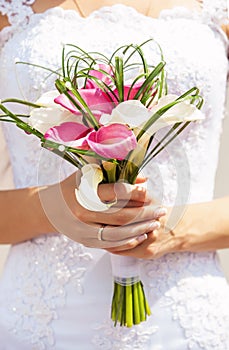 Closeup view of bride holding bouquet of callas