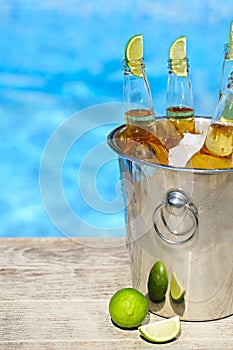 Closeup view of bucket with ice cubes, beer bottles and lime slices