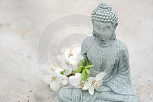 Closeup view of Buddha statuette with blooming cherry tree branch on concrete background with copy space