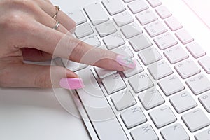Closeup view of a business woman hand typing on wireless computer keyboard on office table. Soft lightning.