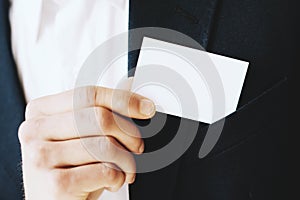 Closeup view of Businessman takes out a blank white business card from his jacket pocket.Horizontal mockup, blurred