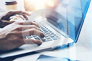 Closeup view of businessman working at sunny office on modern laptop.Male hands typing on notebook keyboard.Blurred