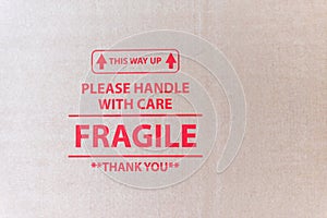 Closeup view of cardboard packaging surface with red printed text This way up please handle with care fragile thank you