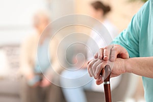 Closeup view of elderly man with cane in nursing home. Assisting senior generation