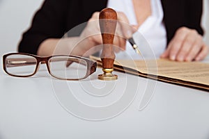 Closeup view of female hand holding stamp and notarized paper. Glassess near