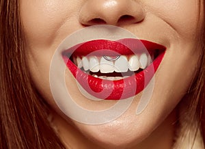 Closeup view of female mouth with bright red lipstick. Beautiful wide smile of young woman with great healthy white