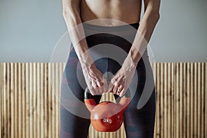 Closeup view of a fit woman in sportswear holding 8 kilograms kettlebell weight photo
