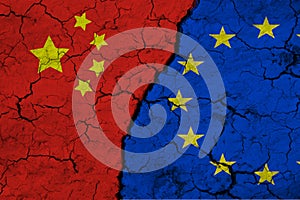 A closeup view of the flag of the European Union and the flag of China against the backdrop of cracked earth. The concept of the