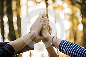 Closeup view of four people joining their hands together high up