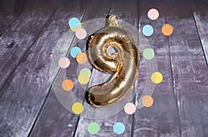 Closeup view of a golden color number nine with decorative papers for birhday